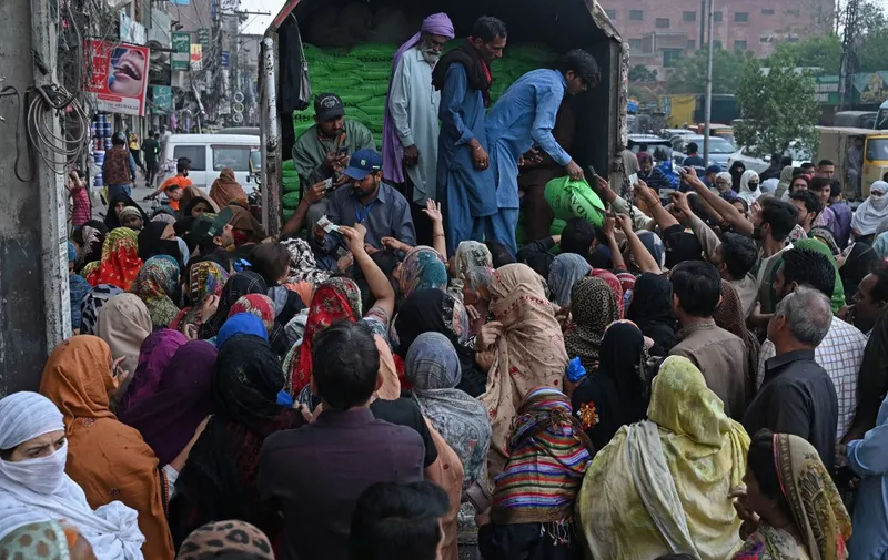 People gather to receive the free bags of flour from a delivery truck at a distribution point ahead of the Muslim holy fasting month of Ramadan, in Lahore on March 20, 2023, following an announcement from Pakistans Prime Minister Shehbaz Sharif to provide free flour to the needy people during the Ramadan in the wake of country's soaring inflation. (Photo by Arif ALI / AFP)