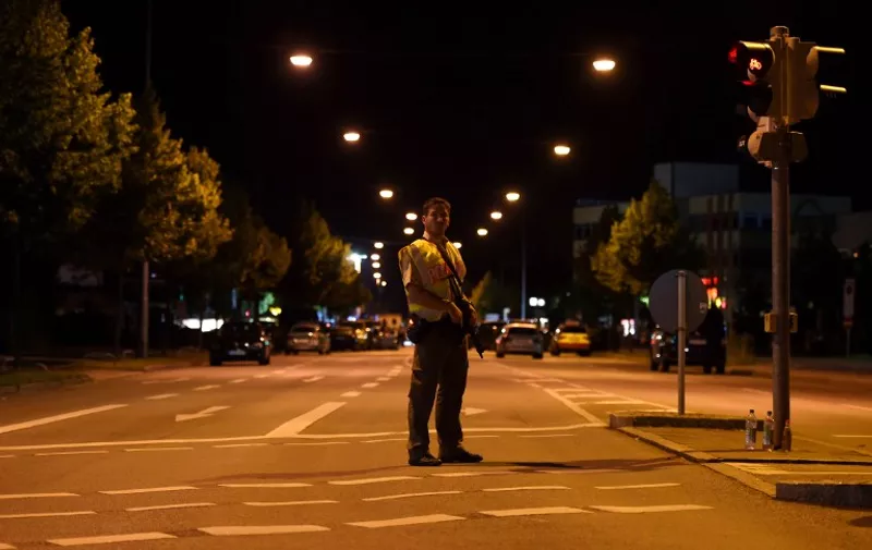 A police officer secures a street near the shopping mall the Olympia Einkaufzentrum (OEZ) in Munich on July 22, 2016 following a shooting earlier. 
Elite German police were hunting for gunmen who went on a shooting rampage at a busy mall in Munich, killing eight people in cold blood in the third attack on civilians in Europe in barely a week. The southern city was in lockdown after the shootings, which saw panicked shoppers fleeing the Olympia mall as anti-terror police launched a massive operation to track down the assailants.
 / AFP PHOTO / CHRISTOF STACHE