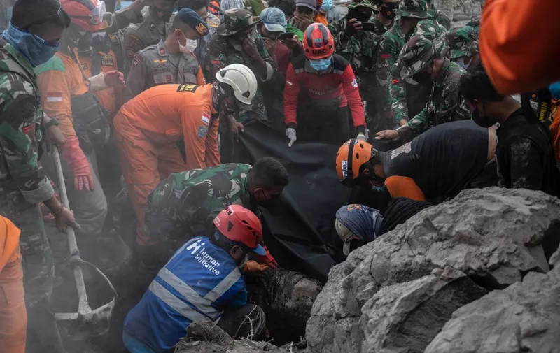 Rescuers removing a body of a victim at Sumber Wuluh village in Lumajang on December 6, 2021, after the Semeru volcano eruption that killed at least 14 people. (Photo by Juni Kriswanto / AFP)