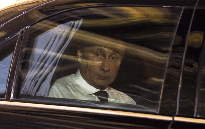 Russian President Vladimir Putin looks on from his car as he leaves the Elysee Palace following his meeting and dinner with his French counterpart in Paris on June 5, 2014. Russian President Vladimir Putin met for talks with French President Francois Hollande, as world leaders engaged in a bout of shuttle diplomacy over Ukraine ahead of D-Day ceremonies. AFP PHOTO / FRED DUFOUR (Photo by FRED DUFOUR / AFP)