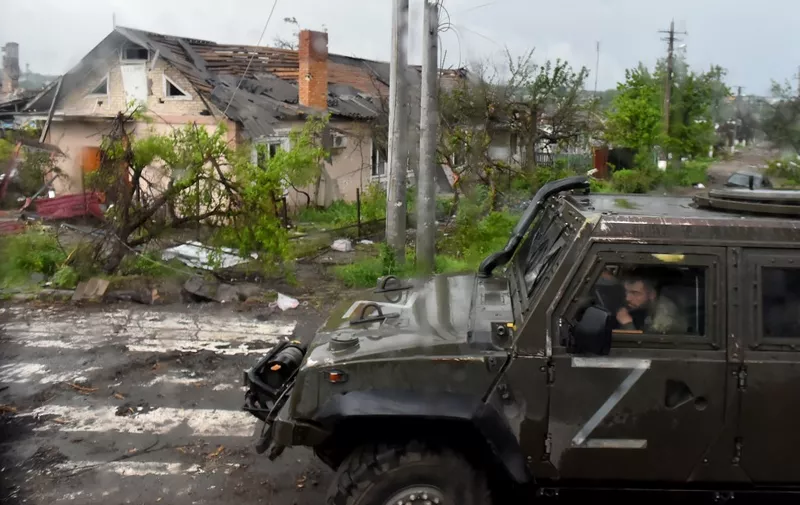 A Russian military vehicle painted with the letter Z drives past destroyed houses in Ukraine's port city of Mariupol on May 18, 2022, amid the ongoing Russian military action in Ukraine. (Photo by Olga MALTSEVA / AFP)