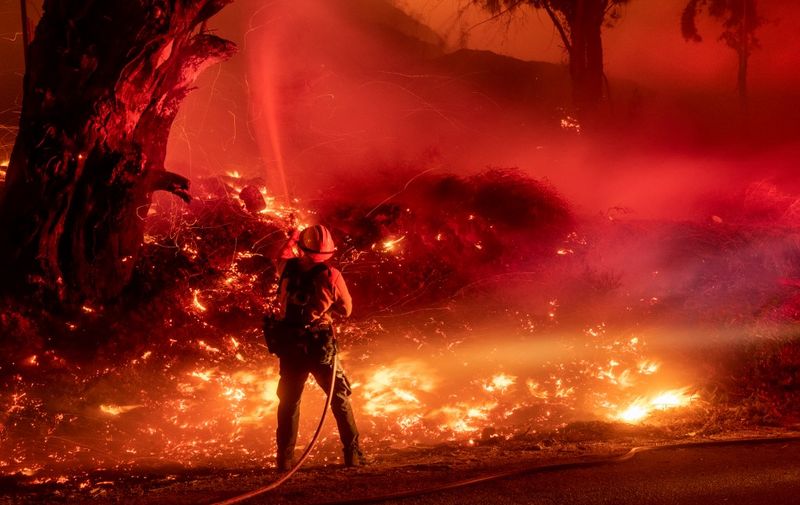 (FILES) In this file photo taken on November 1, 2019 a firefighter douses flames from a backfire during the Maria fire in Santa Paula, California on November 1, 2019. - US President Donald Trump threatened once again on November 3, 2019 to withhold federal aid from California after its Democratic governor criticized his environmental policies.Over the past two weeks, fires have ravaged nearly 100,000 acres (40,000 hectares) in the sprawling western state, where fighters on Sunday were battling the Maria Fire, about 60 miles northwest of Los Angeles. (Photo by Josh Edelson / AFP)