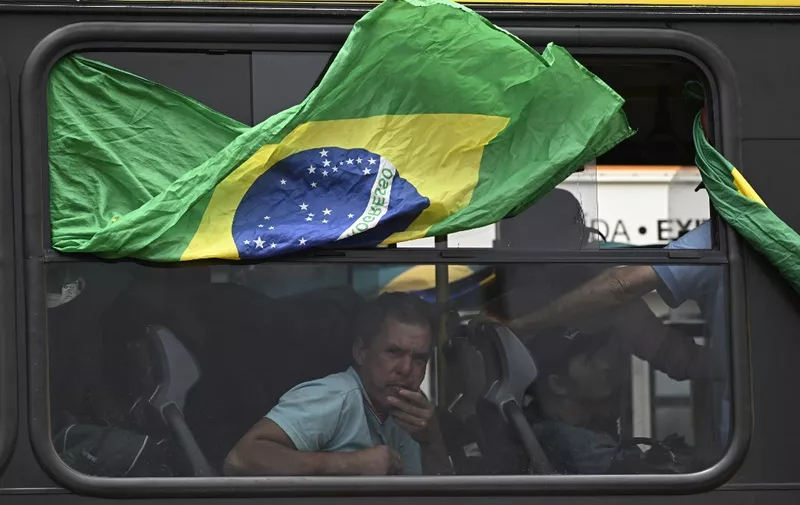 Supporters of Brazil's far-right ex-president Jair Bolsonaro in custody, are taken in buses by police forces to the Federal police headquarters to have their identities and criminal records checked for their possible implication in vandalism acts during the invasions to the Congress, presidential palace and Supreme Court, in Brasilia, on January 9, 2023, a day after the pro-Bolsonaro mob ran riots. - Brazilian security forces locked down the area around Congress, the presidential palace and the Supreme Court Monday, a day after supporters of ex-president Jair Bolsonaro stormed the seat of power in riots that triggered an international outcry. Hardline Bolsonaro supporters have been protesting outside army bases calling for a military intervention to stop Lula from taking power since his election win. (Photo by MAURO PIMENTEL / AFP)