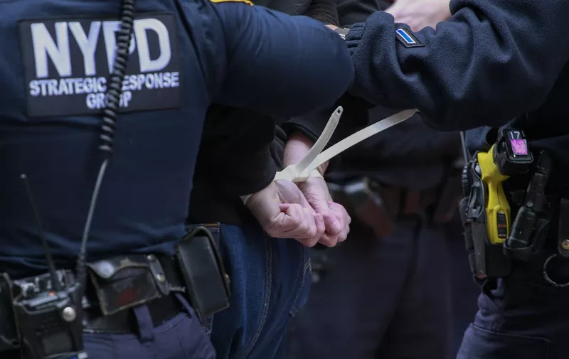 An activist from Extinction Rebellion is arrested by NYPD officers after blocking a street in lower Manhattan during a protest in New York City on April 18, 2022. - Protest group Extinction Rebellion is carrying demonstrations to highlight government inaction on climate change and war. (Photo by Kena Betancur / AFP)