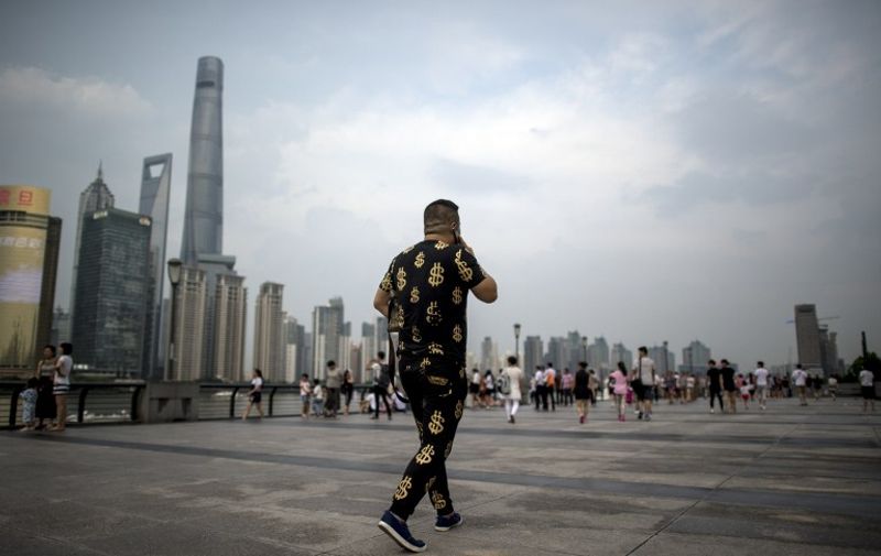 This picture taken on July 15, 2016 shows a man wearing an outfit with golden dollar symbols as he walks down the Bund overlooking the financial district of Pudong in Shanghai. 
China's second-quarter GDP growth was steady at 6.7 percent, the government said on July 15, as the world's second-largest economy seeks stability in the face of a darkening global outlook. / AFP PHOTO / JOHANNES EISELE