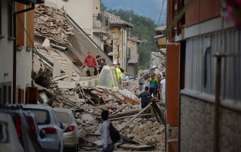 Rescuers and residents search for victim among damaged buildings after a strong earthquake hit Amatrice on August 24, 2016. - Central Italy was struck by a powerful, 6.2-magnitude earthquake in the early hours, which has killed at least three people and devastated dozens of mountain villages. Numerous buildings had collapsed in communities close to the epicenter of the quake near the town of Norcia in the region of Umbria, witnesses told Italian media, with an increase in the death toll highly likely. (Photo by FILIPPO MONTEFORTE / AFP)
