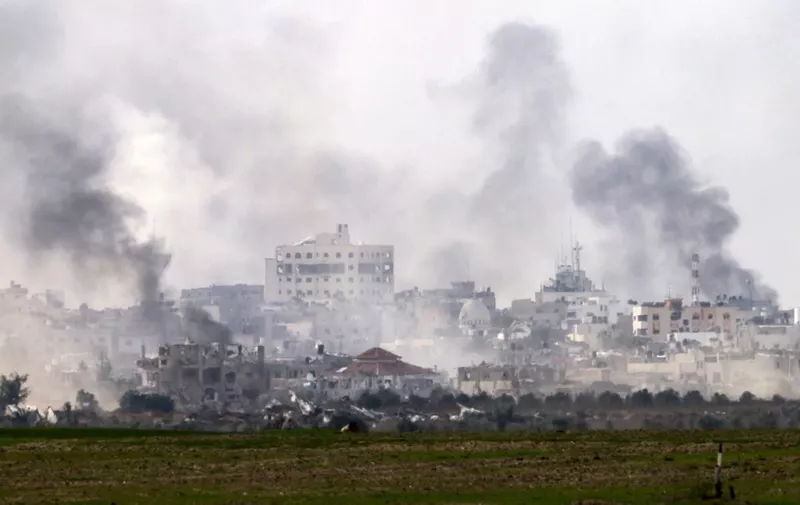 A picture taken from southern Israel near the border with the Gaza Strip on December 10, 2023, shows smoke rising above buildings during Israeli bombardments on Khan Yunis, amid ongoing battles with the Palestinian Hamas militant group. Israeli forces pushed into southern Gaza on December 10, where hundreds of thousands of civilians have fled in search of shelter from bombardments and intense fighting with Hamas militants. (Photo by Menahem KAHANA / AFP)