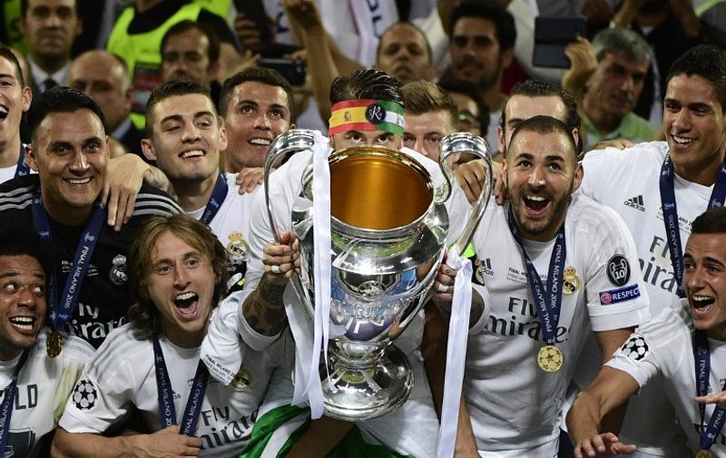 Real Madrid's Spanish defender Sergio Ramos (C) lifts the trophy next to Real Madrid's Croatian midfielder Luka Modric (L) and Real Madrid's French forward Karim Benzema (R) after Real Madrid won the UEFA Champions League final football match between Real Madrid and Atletico Madrid at San Siro Stadium in Milan, on May 28, 2016. / AFP PHOTO / PIERRE-PHILIPPE MARCOU