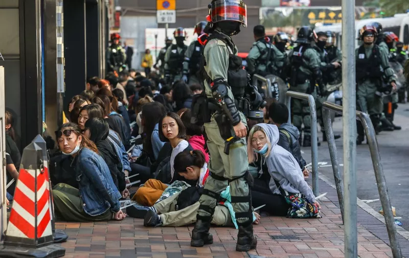 People are detained by police near the Hong Kong Polytechnic University in Hung Hom district of Hong Kong on November 18, 2019. - Pro-democracy demonstrators holed up in a Hong Kong university campus set the main entrance ablaze November 18 to prevent surrounding police moving in, after officers warned they may use live rounds if confronted by deadly weapons. (Photo by DALE DE LA REY / AFP)