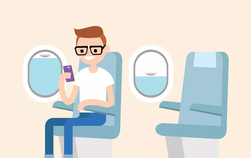 Funny red head nerd sitting on the plane and holding his smart phone / editable flat vector illustration