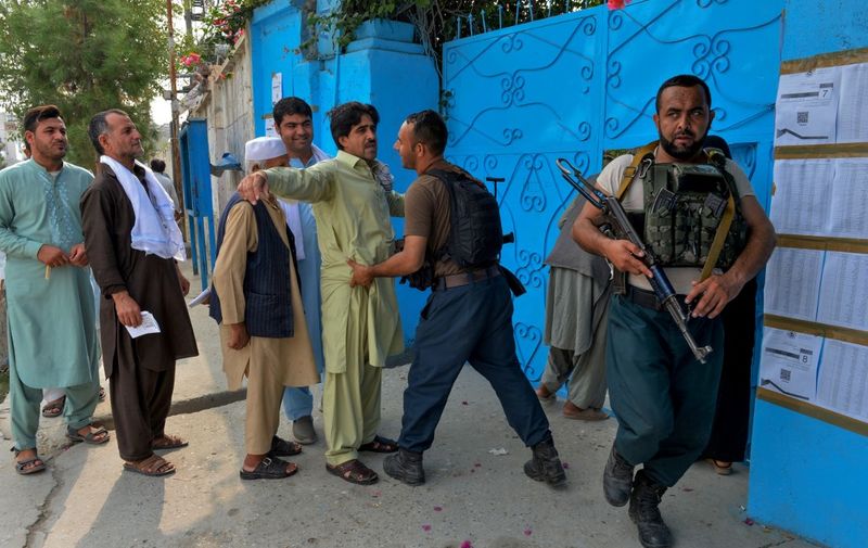 A security force personnel checks a man outside a polling station in Jalalabad on September 28, 2019. - Insurgents worked to disrupt Afghanistan's presidential election on September 28, with a series of blasts reported across the country as voters headed to the polls and troops flooded the streets of the capital. (Photo by Noorullah SHIRZADA / AFP)