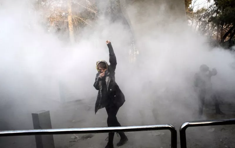 An Iranian woman raises her fist amid the smoke of tear gas at the University of Tehran during a protest driven by anger over economic problems, in the capital Tehran on December 30, 2017.
Students protested in a third day of demonstrations sparked by anger over Iran's economic problems, videos on social media showed, but were outnumbered by counter-demonstrators. / AFP PHOTO / STR