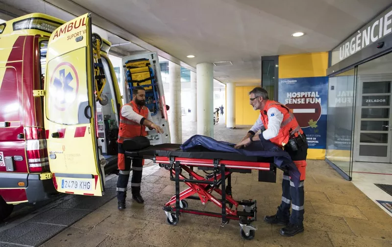Two men ready an ambulance outside the Son Espases University Hospital in Palma de Mallorca where a British man has been diagnosed with coronavirus, on February 9, 2020. (Photo by STRINGER / AFP)