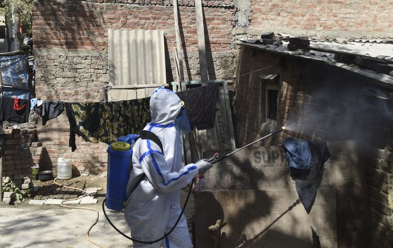 A health worker sprays sanitizer outside a house as a precautionary measure against the bird flu in Sola area, on the outskirts of Ahmedabad on March 5, 2021. (Photo by SAM PANTHAKY / AFP)