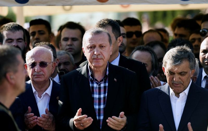 Turkey's President Recep Tayyip Erdogan (C) and former Turkish president Abdullah Gul (R) pray during the funeral of a victim of the coup attempt in Istanbul on July 17, 2016. 
Turkish President Recep Tayyip Erdogan vowed today to purge the "virus" within state bodies, during a speech at the funeral of victims killed during the coup bid he blames on his enemy Fethullah Gulen. / AFP PHOTO / BULENT KILIC