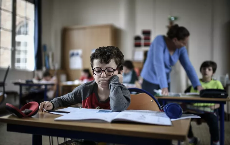 A child of medical staff member read in the classroom at the Eugene Napoleon Saint-Pierre Fourier private school on April 30, 2020, in Paris, on the 45th day of a strict lockdown in France to stop the spread of COVID-19 (novel coronavirus). (Photo by STEPHANE DE SAKUTIN / AFP)