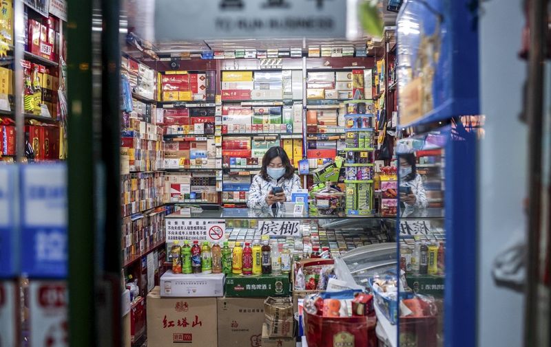 A vendor wearing a protective facemask waits for customers at a shop in Beijing on February 21, 2020. - Two more people died from the new coronavirus in Iran, infections nearly doubled in South Korea, and clusters surfaced in Chinese prisons on February 21, rekindling concerns about an epidemic that has killed more than 2,200 people in China. (Photo by NICOLAS ASFOURI / AFP)