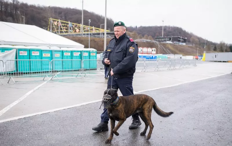 An Austrian police officer patrols with a dog at an empty refugee centre in Spielfeld at the Austrian-Slovenian border as Austria imposes a new daily migrant limit on February 19, 2016. 
 / AFP PHOTO / Rene Gomolj