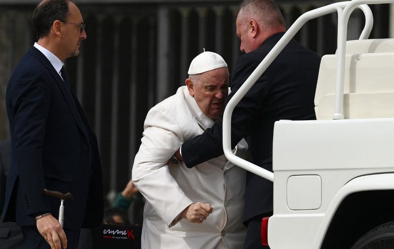 Pope Francis is helped get up the popemobile car as he leaves on March 29, 2023 at the end of the weekly general audience at St. Peter's square in The Vatican. - Pope Francis has been at the Gemelli Hospital in Rome since the afternoon of March 29, 2023 for some previously scheduled check-ups, the Holy See press director said. (Photo by Vincenzo PINTO / AFP)