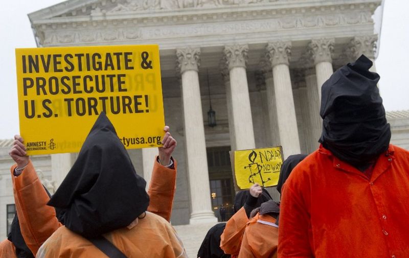 Protesters wearing orange prison jump suits and black hoods on their heads march during a protest against holding detainees at the military prison in Guantanamo Bay during a demonstration in front of the US Supreme Court in Washington, DC, on January 11, 2012, the 10th anniversary of the arrival of the first group of detainees to be held at the prison. Protesters marched down Pennsylvania Avenue from the White House, past the US Capitol before finishing at the US Supreme Court. AFP PHOTO / Saul LOEB