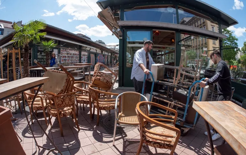 A worker removes extra chairs at the 'Orient Accident' restaurant at Naschmarkt market in Vienna, Austria on May 12, 2020 a few days before restaurants, cafes and bars reopen after the new coronavirus lockdown. - Restaurants, cafes and bars will reopen from May 15, 2020 with a limited number of customers who will have to use face masks. (Photo by JOE KLAMAR / AFP)
