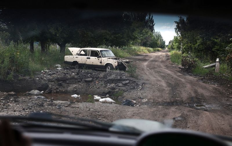 This photograph taken on July 12, 2023, shows a destroyed car on a road in the village Verkhnyokamianske, eastern Ukraine, on July 12, 2023, amid the Russian invasion of Ukraine. (Photo by Anatolii Stepanov / AFP)