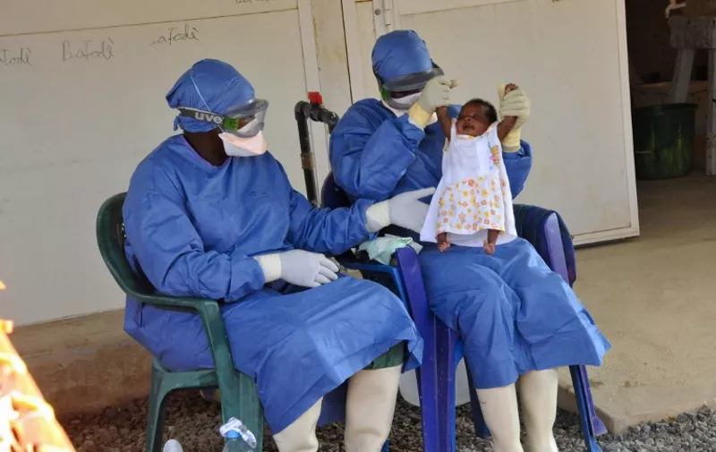 Medical workers present Noubia, the last known patient to contract Ebola in Guinea, during her release from a Doctors Without Borders treatment center in Conakry on November 28, 2015. The 34-day-old baby, officially declared treated on November 16, was presented by personal from the treatment center, with applause, during an emotional ceremony, in the presence of her family. AFP PHOTO / CELLOU BINANI / AFP / CELLOU BINANI