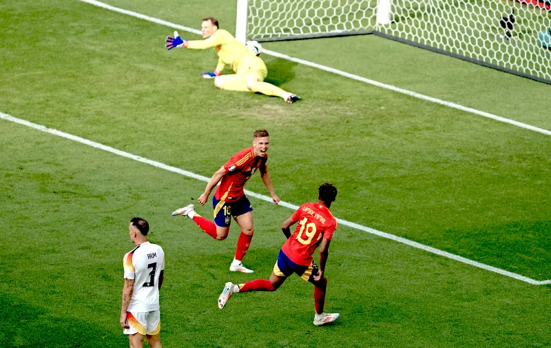 Spain's Dani Olmo, centre, celebrates with Spain's Lamine Yamal after scoring the opening goal during a quarter final match between Germany and Spain at the Euro 2024 soccer tournament in Stuttgart, Germany, Friday, July 5, 2024. (AP Photo/Michael Probst)