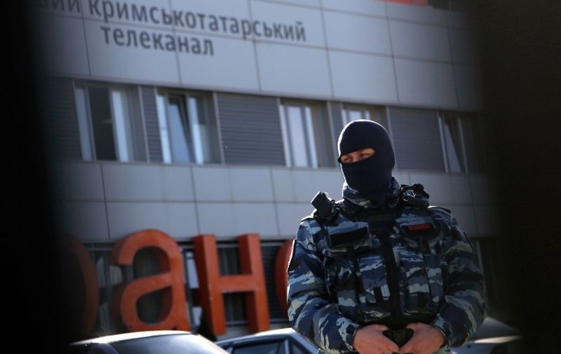 An officer of the Russian riot police force OMON stands guard outside the offices of Crimean Tatar TV channel ATR in Simferopol on January 26, 2015. A search was conducted on January 26 at the offices of the television channel of the Muslim  Crimean Tatar minority, the assistant director general of ATR channel, Lilia Boudjourova, told AFP. AFP PHOTO / MAX VETROV / AFP / MAX VETROV