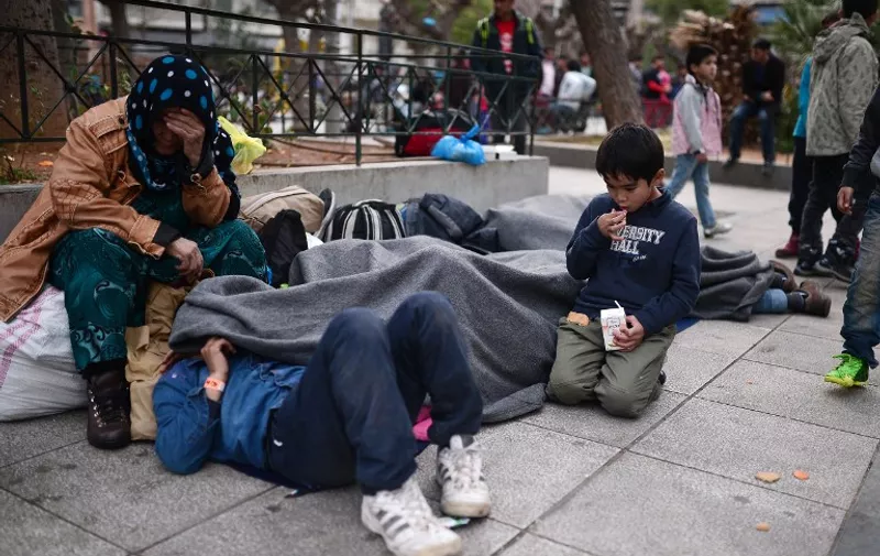 An Afghan family rests at Victoria Square in central Athens, where stranded migrants and refugees, many from Afghanistan, have found temporary shelter, on February 24, 2016.
Greece has expressed "displeasure" to the EU over tougher border controls by Balkan countries that have stranded thousands of migrants in the country, Prime Minister Alexis Tsipras' office said on February 23. / AFP / LOUISA GOULIAMAKI