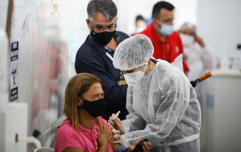 A woman reacts after receiving a dose of the CoronaVac vaccine against Covid-19 at a vcccination post in Brasília, Brazil, on January 07, 2022. (Photo by Sergio Lima / AFP)