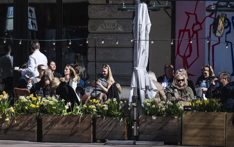 People enjoy the spring weather as they sit at a restaurant in Stockholm on April 15, 2020, during the coronavirus COVID-19 pandemic. (Photo by Jonathan NACKSTRAND / AFP)