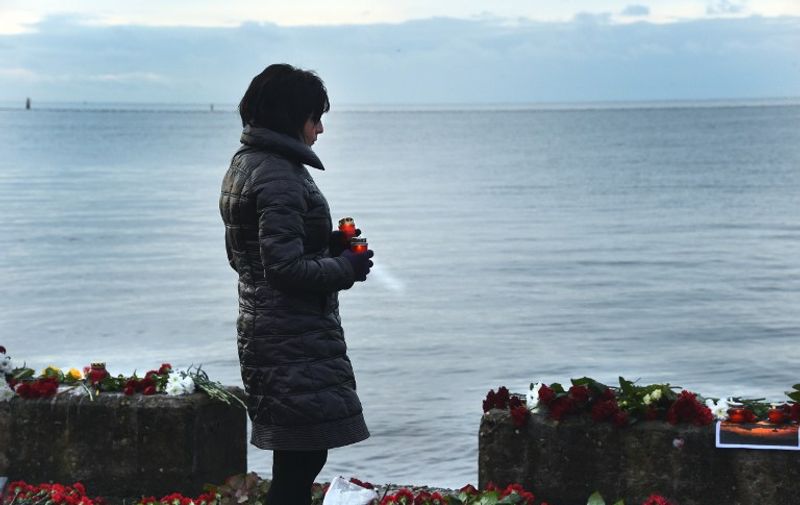 A woman holds candles at a memorial on a pier outside Sochi, on December 26, 2016, as Russia observes a national day of mourning a day after a military plane carrying 92 people, including dozens of members of the Red Army Choir, crashed in the Black Sea.
The Russian defence ministry told agencies there was no sign of any survivors at the crash site and that 10 bodies had been recovered off the coast of the resort city of Sochi, as authorities pledged to dispatch an additional 100 divers to aid in the search.
 / AFP PHOTO / VASILY MAXIMOV