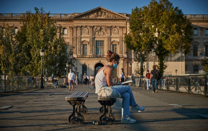 PARIS, FRANCE - SEPTEMBER 14: A Parisian sits on the Pont des Arts bridge wearing a face mask since the city made the wearing of a mask compulsory after the recent surge of COVID-19 cases in the city on September 14, 2020 in Paris, France. On Saturday, the number of new daily cases exceeded 10,000, with infection rates rising among all age groups. (Photo by Kiran Ridley/Getty Images)