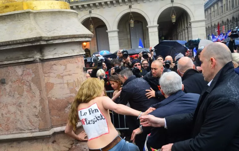 FRANCE, Paris : A Femen activist tries to block the president of France's far-right political party Front National (FN) Marine Le Pen as she lays flowers at the foot of a statue of Joan of Arc during a traditional rally in her honour on May 1, 2015 in Paris.  - CITIZENSIDE/FRANCOIS PAULETTO