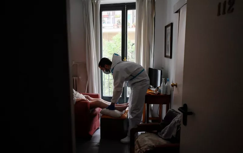 Spanish physiotherapist Vicente Barrios works out with an isolated resident at an elderly people nursing home in Madrid on April 24, 2020. - What mistakes led to so many deaths? Spain begins to investigate the tragedies behind the closed doors of its retirement homes, where thousands of deaths are attributed to coronavirus. (Photo by OSCAR DEL POZO / AFP)