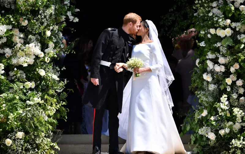 Britain's Prince Harry, Duke of Sussex kisses his wife Meghan, Duchess of Sussex as they leave from the West Door of St George's Chapel, Windsor Castle, in Windsor, on May 19, 2018 after their wedding ceremony. (Photo by Ben STANSALL / POOL / AFP)