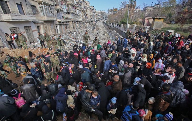 Syrian residents fleeing the violence gather at a checkpoint, manned by pro-government forces, in the Maysaloun neighbourhood of the northern embattled Syrian city of Aleppo on December 8, 2016.
Syria's army battled to take more ground from rebels in Aleppo after President Bashar al-Assad said victory for his troops in the city would be a turning point in the war. / AFP PHOTO / Youssef KARWASHAN