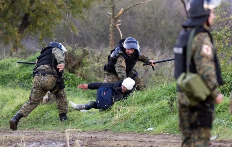 Macedonian policemen (with headgear) hold back a migrant within clashes near Gevgelija at the Greek-Macedonian border on November 26, 2015. Over 200 migrants on November 26 tried to break through barbed wire fences to cross from Greece into Macedonia, which imposed new border restrictions last week, throwing stones at police. At least five of the migrants managed to get across in the assault as the crowd shouted "Open the border" to the Macedonia police ranged in front of them. AFP PHOTO / ROBERT ATANASOVSKI / AFP / ROBERT ATANASOVSKI