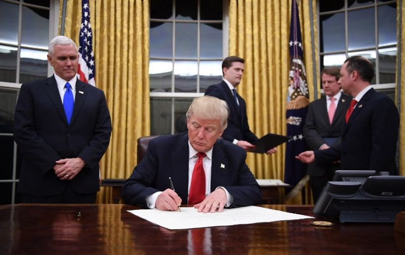 US President Donald Trump signs a confirmation for John Kelly as US Secretary of Homeland Security, as Vice President Mike Pence (L) and White House Chief of Staff Reince Priebus (R) look on, in the Oval Office of the White House in Washington, DC, January 20, 2017. / AFP PHOTO / JIM WATSON
