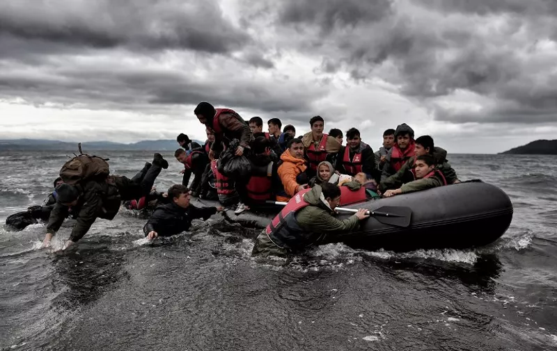 Migrants dive into the sea to help other refugees and migrants to land on the Greek island of Lesbos, on October 24, 2015, after crossing the Aegean sea from Turkey. Bulgaria, Romania and Serbia on October 24 threatened to close their borders if EU countries stopped accepting migrants, as European leaders prepared for a mini summit on the continent's worst refugee crisis since World War II. AFP PHOTO / ARIS MESSINIS