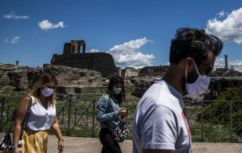 People wearing a face mask visit the archeological site of Pompeii on May 26, 2020, as the country eases its lockdown aimed at curbing the spread of the COVID-19 infection, caused by the novel coronavirus. - Italy's world-famous archeological site Pompeii reopened to the public on May 26,bBut with foreign tourists still prohibited from travel to Italy until June, the site that attracted just under 4 million visitors in 2019 is hoping that for now, Italian tourists can make up at least a fraction of the difference. (Photo by Tiziana FABI / AFP)