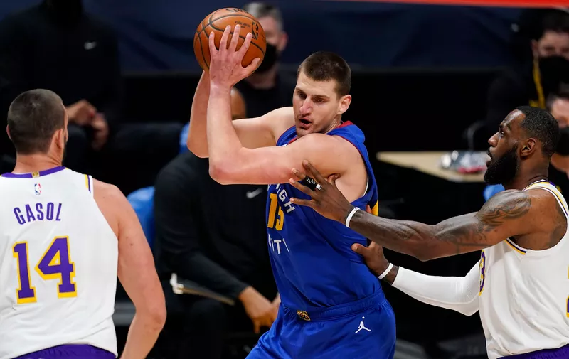 Denver Nuggets center Nikola Jokic, center, looks to pass the ball as Los Angeles Lakers center Marc Gasol, left, and forward LeBron James defend in the first half of an NBA basketball game Sunday, Feb. 14, 2021, in Denver. (AP Photo/David Zalubowski)