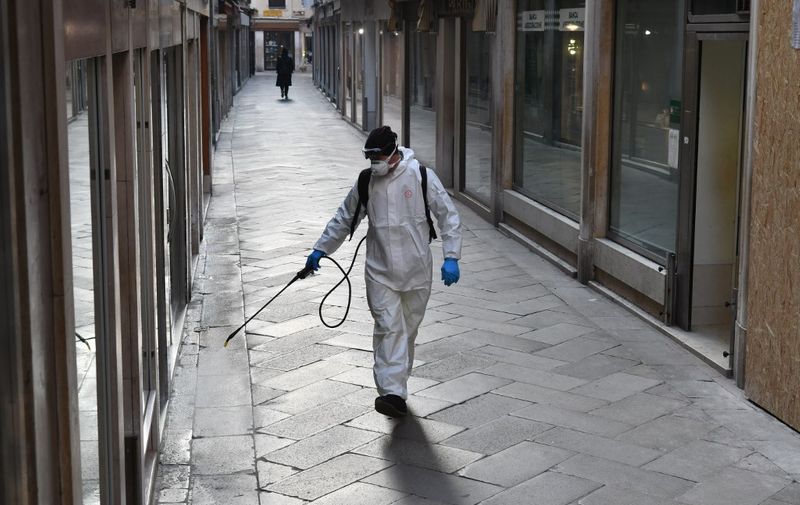 An employee of the municipal company Veritas sprays disinfectant in public areas in Venice on March 11, 2020, as part of precautionary measures against the spread of the new coronavirus COVID-19, a day after Italy imposed unprecedented national restrictions on its 60 million people Tuesday to control the deadly COVID-19 coronavirus. (Photo by MARCO SABADIN / AFP)