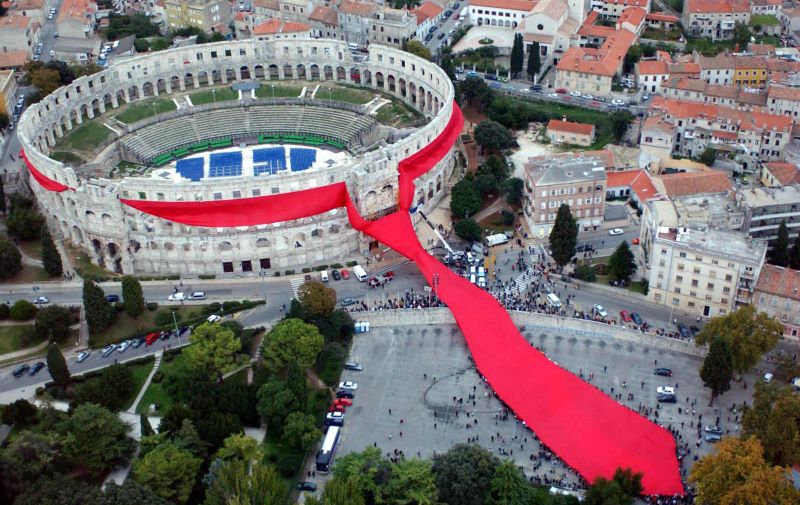 18.10.2003., Pula - Oko pulske arene svezana je najveca kravata na svijetu. Uz bogat umjetnicki i zabavni spektakl zsvrsena je realizacija umjetnicke instalacije "Kravata oko Arene" autora Marijana Busica, ravnatelja Udruge Academia Cravatica. Ovom instalacijom Hrvatska, domovina kravate, ulazi u Guinnessovu knjigu rekorda. Kravata je zarko crvene boje, teska 800 kilograma, siroka 8 metara, a u svom najsirem dijelu 26 metara. rPhoto: Dusko Marusic/PIXSELL