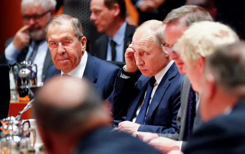 Russian President Vladimir Putin (2ndL) and acting Russian Foreign Minister Sergei Lavrov (L) sit at their places at the start of a Peace summit on Libya at the Chancellery in Berlin, on January 19, 2020. - World leaders gather in Berlin on January 19, 2020 to make a fresh push for peace in Libya, in a desperate bid to stop the conflict-wracked nation from turning into a "second Syria". Chancellor Angela Merkel will be joined by the presidents of Russia, Turkey and France and other world leaders for talks held under the auspices of the United Nations. (Photo by HANNIBAL HANSCHKE / POOL / AFP)