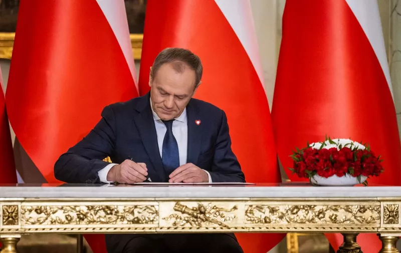 Newly-appointed Polish Prime Minister Donald Tusk signs a document during his formal swearing-in ceremony at the Presidential Palace in Warsaw, Poland, on December 13, 2023. (Photo by Wojtek Radwanski / AFP)