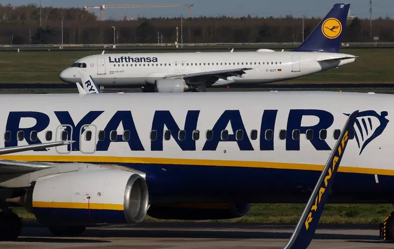 A passenger jet of German airline Lufthansa lands on the runway as an aircraft of low-cost Irish airline Ryanair taxis at the Berlin-Brandenburg airport in Schoenefeld near Berlin, on April 4, 2024. (Photo by David GANNON / AFP)