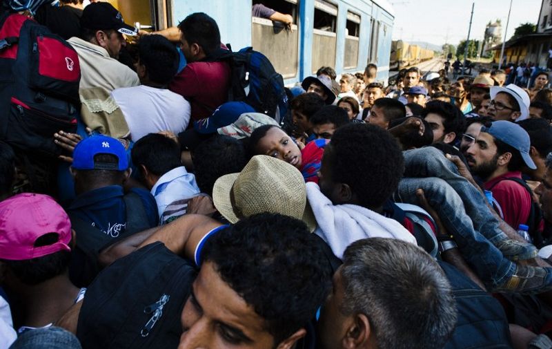 Migrants rush as they try to get on a train heading to the border with Serbia at the train station of Gevgelija, on the Macedonian-Greek border, on August 9, 2015. Non-EU Serbia's frontier with Hungary, which is in the bloc's passport-free Schengen zone, has become a major crossing point for the huge numbers of migrants entering the EU. AFP PHOTO / DIMITAR DILKOFF