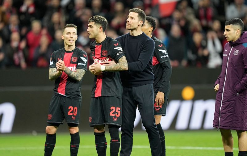 Leverkusen's head coach Xabi Alonso, centre, embraces Exequiel Palacios at the end of the Europa League round of sixteen, second leg, soccer match between Bayer Leverkusen and Qarabag FK at the BayArena in Leverkusen, Germany, Thursday, March 14, 2024. (AP Photo/Martin Meissner)